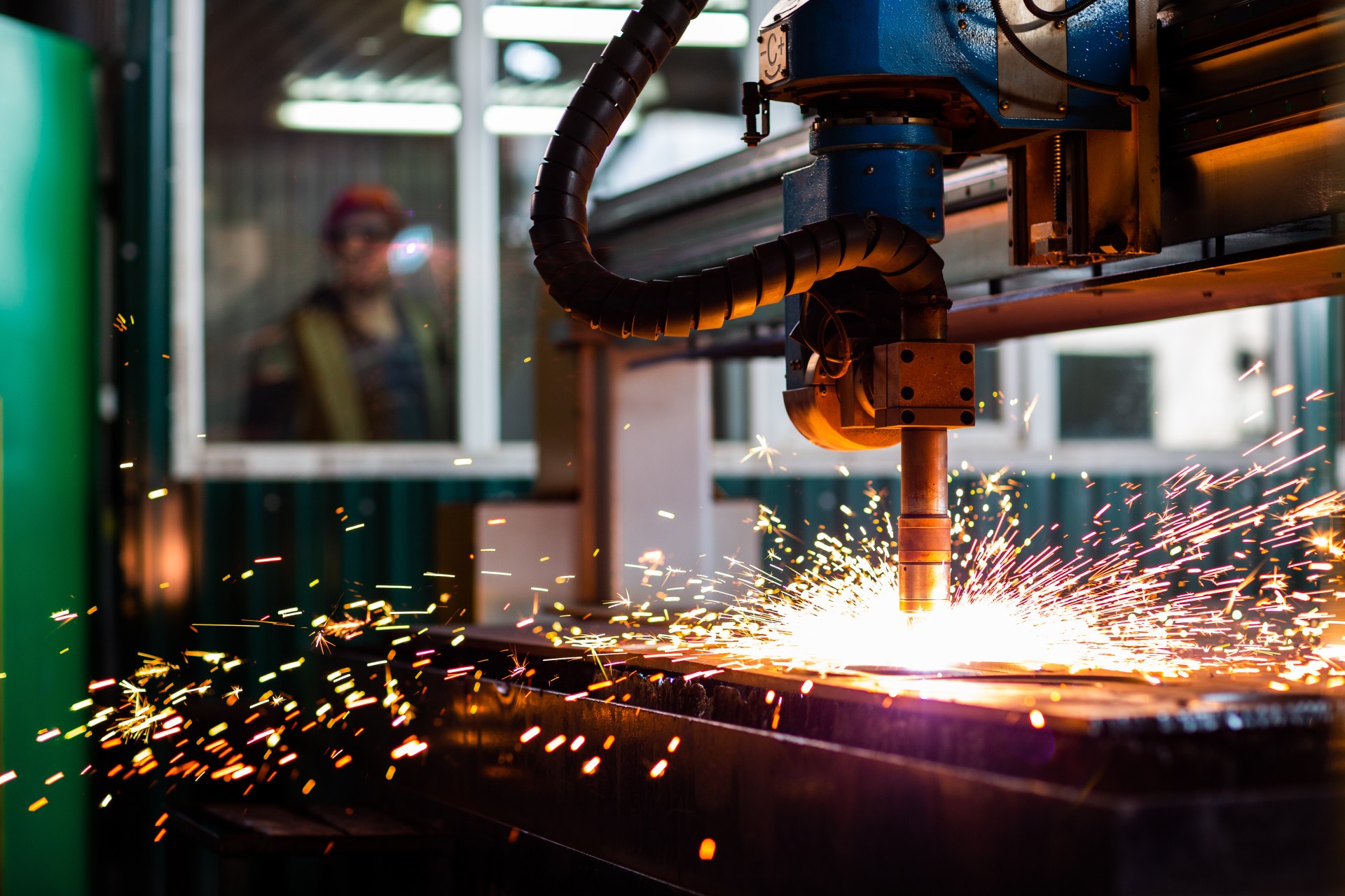 Sparks fly around a plasma cutter at a workplace.