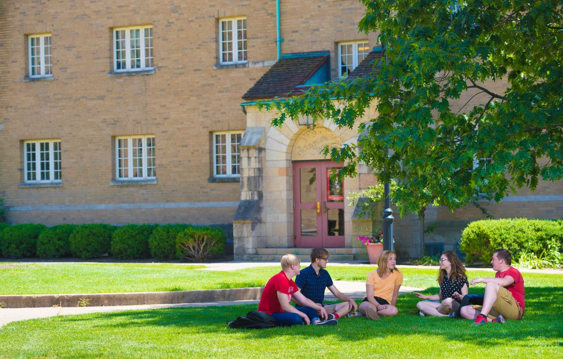 A group of college students sits on the campus at Bradley University.