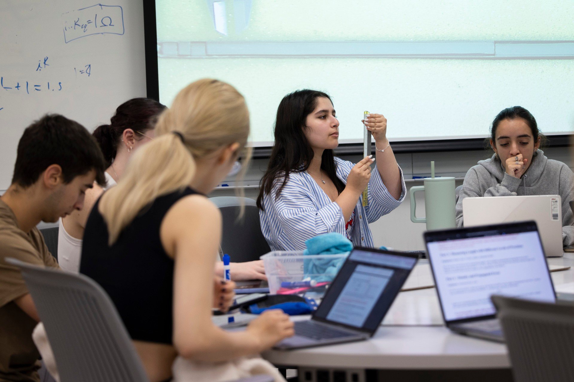 A student looks attentively at a ruler in a physics lab 